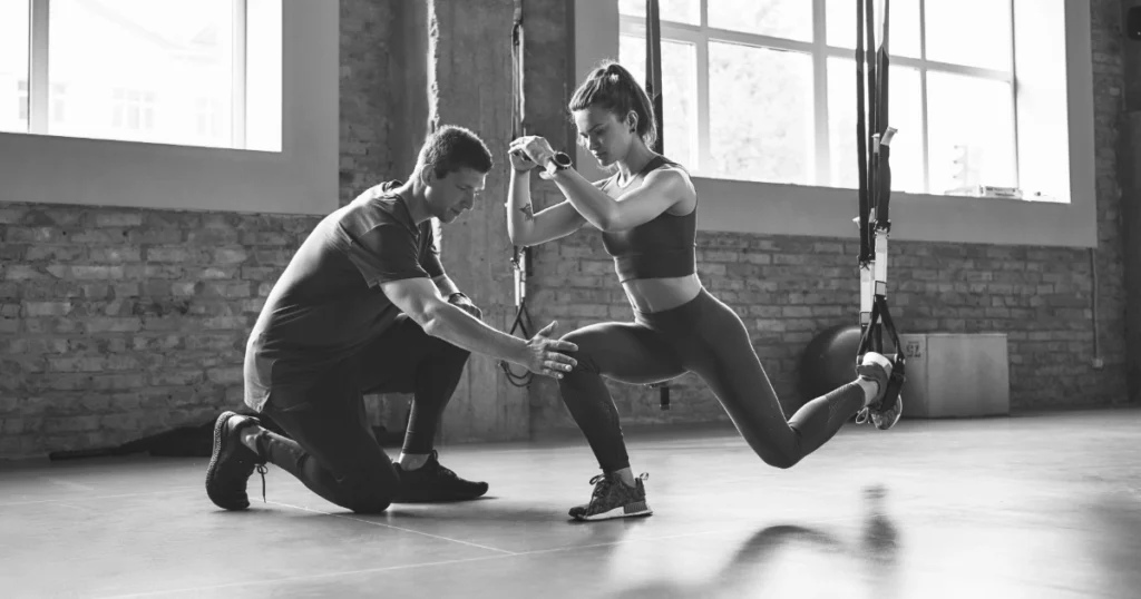 Trainer guiding a woman through a stability exercise during physical therapy and performance training